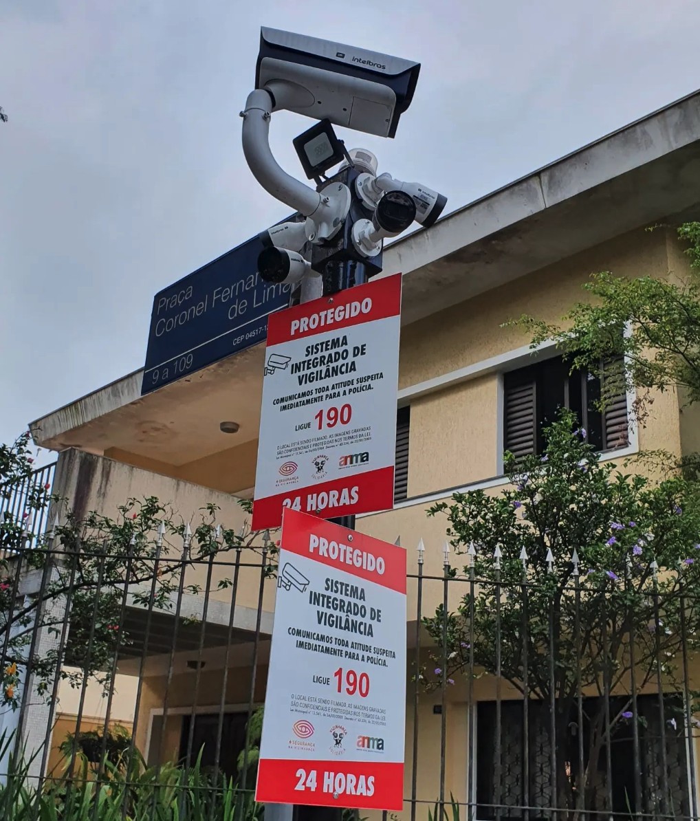 Poste de câmeras perimetrais da ANMA em frente à Praça Coronel Fernandes de Lima, com a placa PROTEGIDO — Sistema Integrado de Vigilância